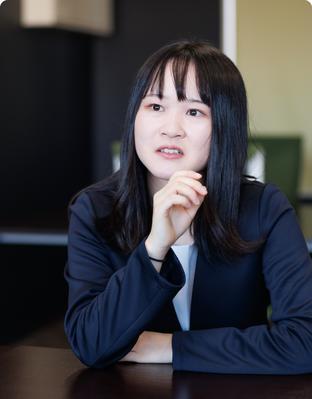 仕事への想いややりがいを真剣な表情で語る、スーツ姿の女性社員。社員インタビューのワンシーン。