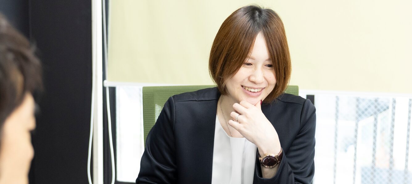 笑顔で談笑する女性スタッフ。オフィスでの打ち合わせの様子。