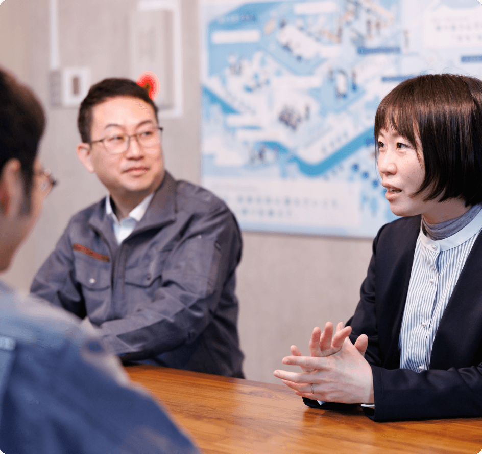 社内のミーティングで、笑顔を交えながら意見を交わす女性社員と男性社員。風通しの良い職場環境を象徴するシーン