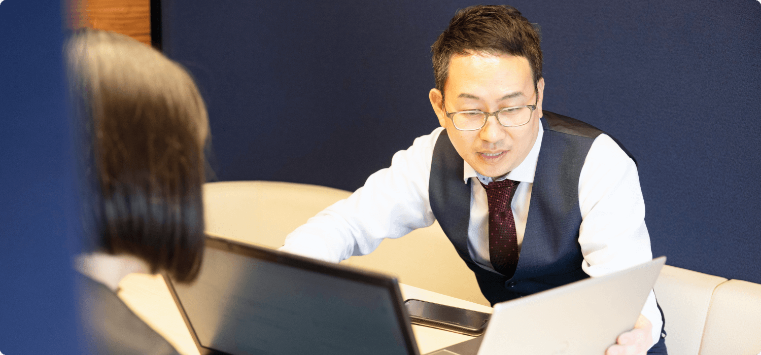 後輩の疑問に丁寧に答える先輩社員。単なる作業員ではなく、知識を共有し、共に課題を解決する「建物点検コンサルタント」としての育む文化。