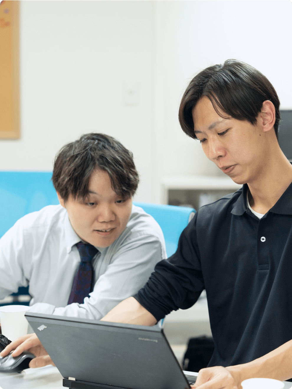 男性社員がパソコンを見ながら会話している様子