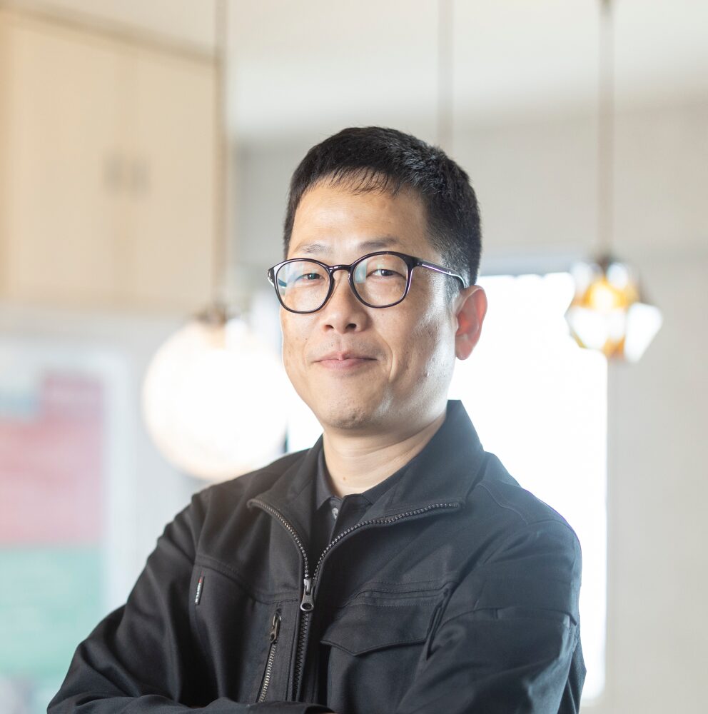 作業着を着用し、腕組みをして微笑む男性