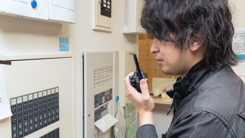 現場で無線機を使い、迅速かつ正確に連携を取る技術スタッフ。トラブルを未然に防ぎ、建物の安全を24時間体制で守る「Guardians」の姿。