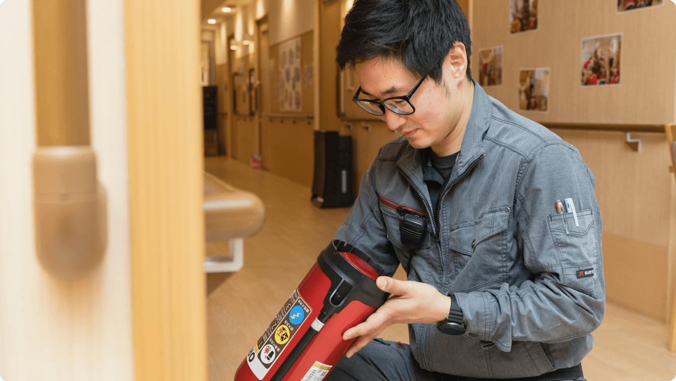 消火器の動作状況を一台ずつ入念に点検する技術スタッフ。火災から施設を守るための、妥協のない保守管理体制。