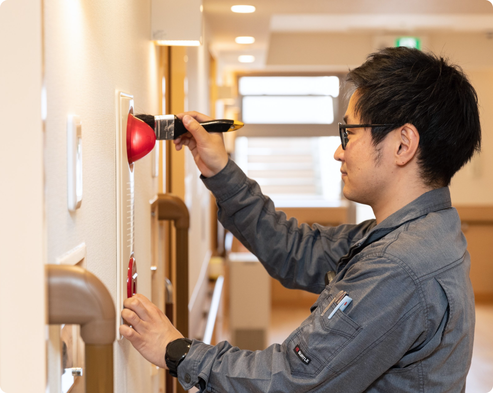 火災報知器の隙間を専用ブラシで丁寧に清掃。有事の際に確実に動作させるための、細部まで妥協しない日常点検。