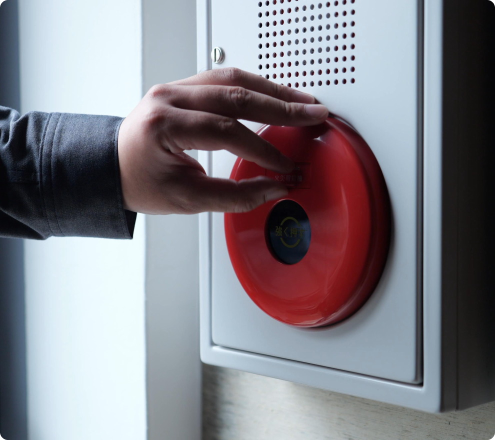 非常ベル(発信機)の動作確認を行う手元のアップ。有事の際に確実に機能させるための、定期的な精密点検の様子。